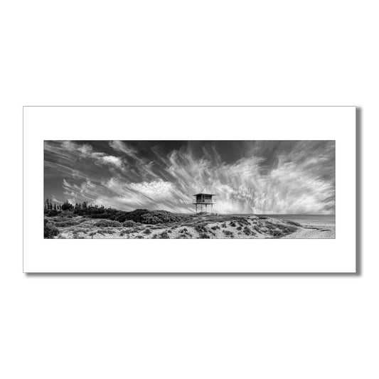 Escape to the coast with this breathtaking black and white panorama  art print of Semaphore Beach, Australia. Featuring a historic lookout tower and awe-inspiring clouds, this limited-edition print is a must-have for any art lover or traveller