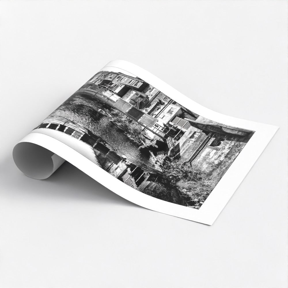 This evocative black and white art poster print transports you to a simpler time. Laundry drying on a clothesline, a rustic bridge, and charming cottages create a scene of peaceful village life